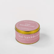 Oud Sandalwood soy wax candle in round pink and gold tin on white background